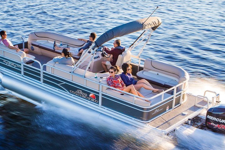 Pontoon boat on water with six people relaxing under a canopy.